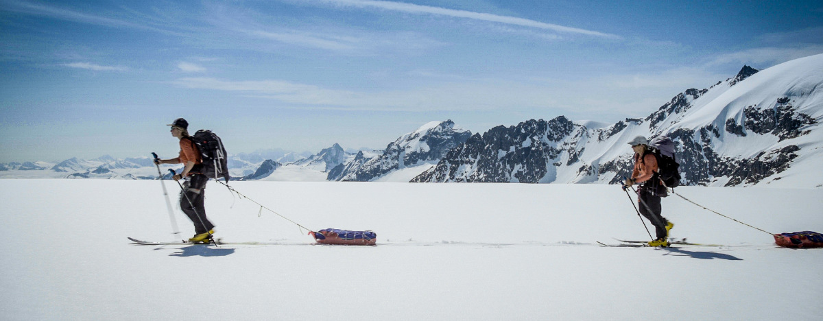 Two people Telemark skiing across a snow field